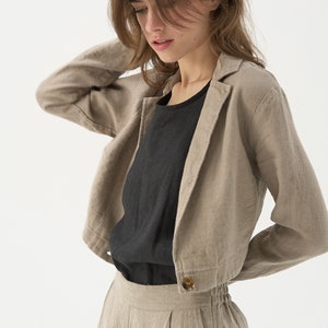 Cropped linen jacket with classic jacket lapels. Ends around navel. One large button at the bottom hem.