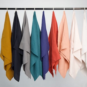 Peut inclure: Huit torchons en lin suspendus à un support. Les torchons sont de différentes couleurs, notamment jaune moutarde, bleu marine, gris, turquoise, bleu marine, corail, pêche et blanc.