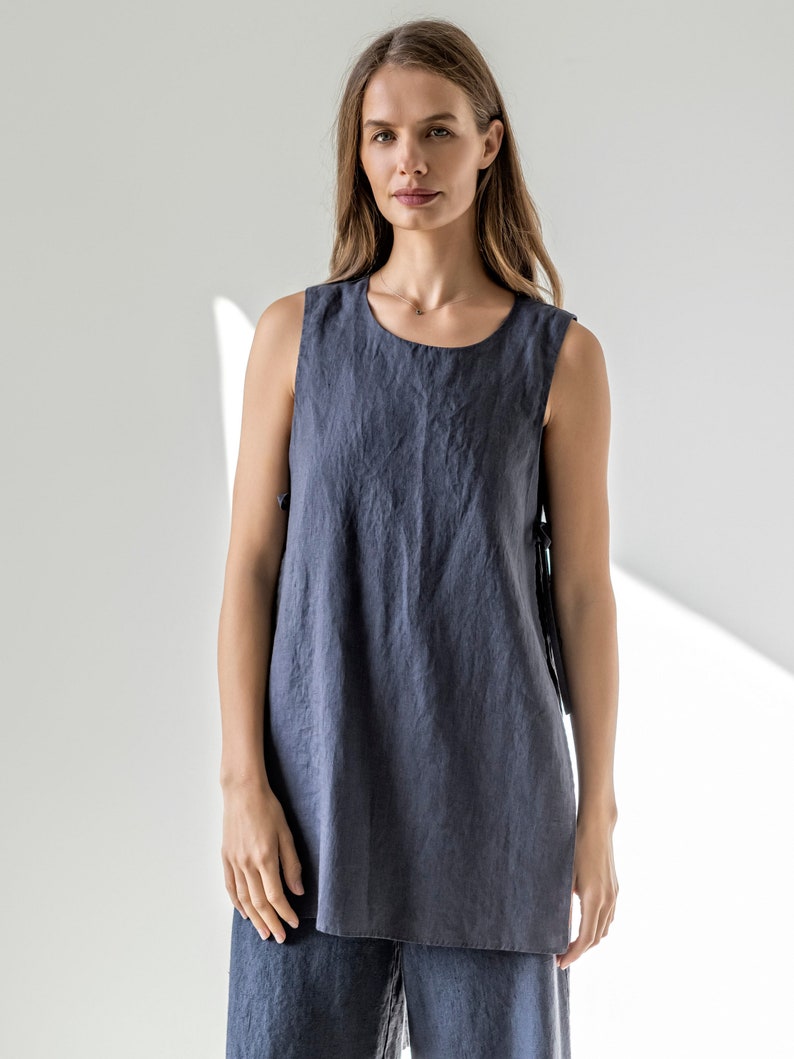 Puede incluir: Una mujer lleva una t&uacute;nica de lino azul oscuro sin mangas con cuello redondo. La parte superior tiene un corte holgado y una longitud ligeramente m&aacute;s larga. La mujer lleva pantalones de lino a juego.