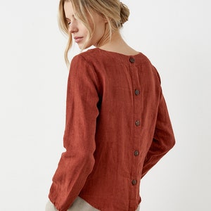 May include: A rust-colored linen shirt with long sleeves and a button-up back.