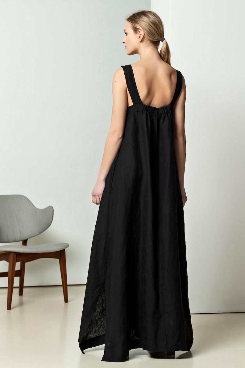 May include: A black linen maxi dress with thin straps and a gathered waist. The dress has a slightly A-line silhouette and a high neckline.