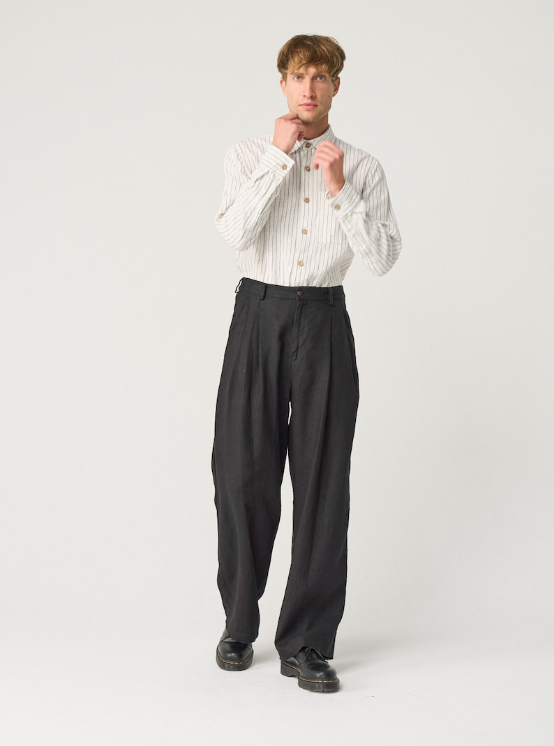 May include: A person wearing a white striped long-sleeve shirt with black pants and black shoes.