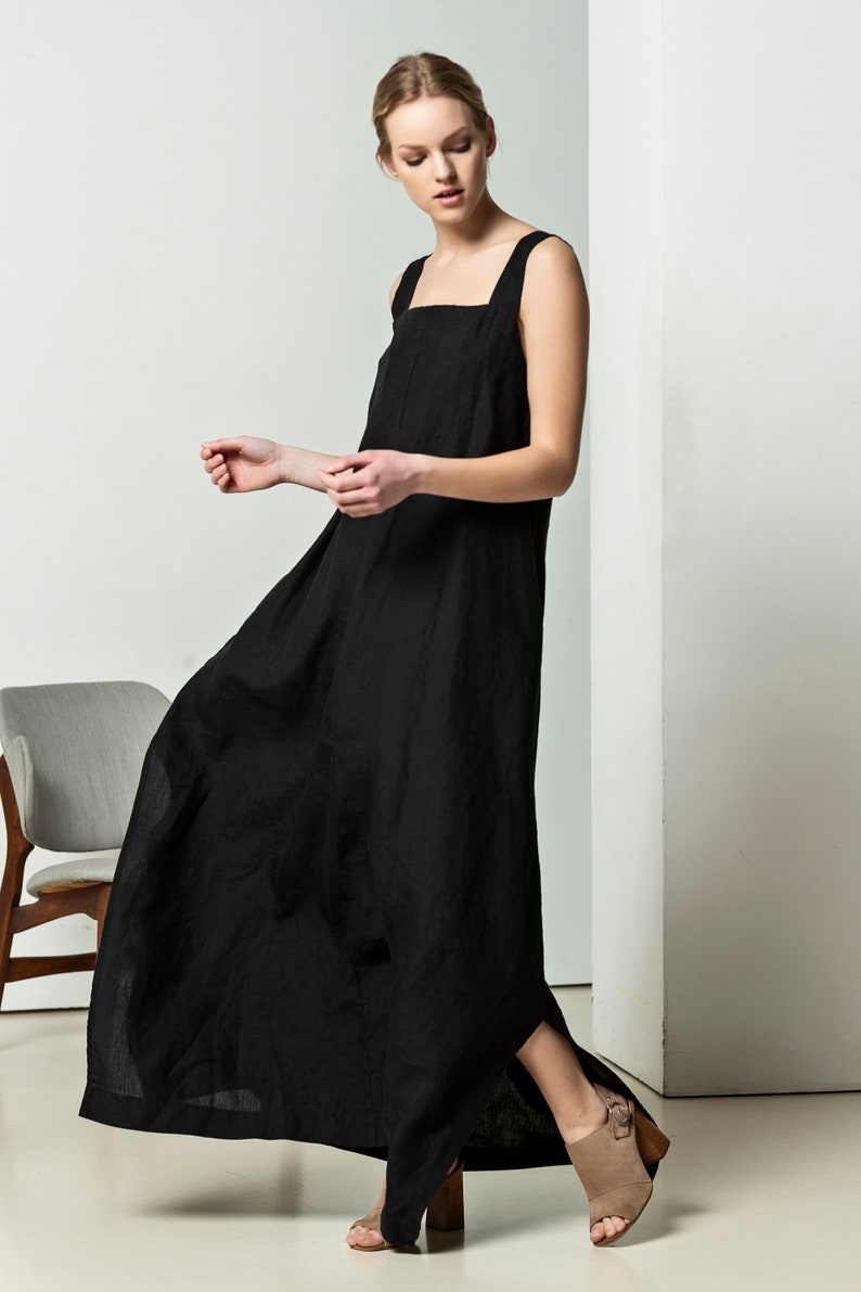 May include: A black linen maxi dress with a square neckline and thin straps. The dress has a side slit and a relaxed fit.