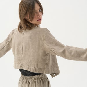 Cropped linen jacket with classic jacket lapels. Back photo. There's a stylised seam placed at the middle back, going through the entire length of the jacket.