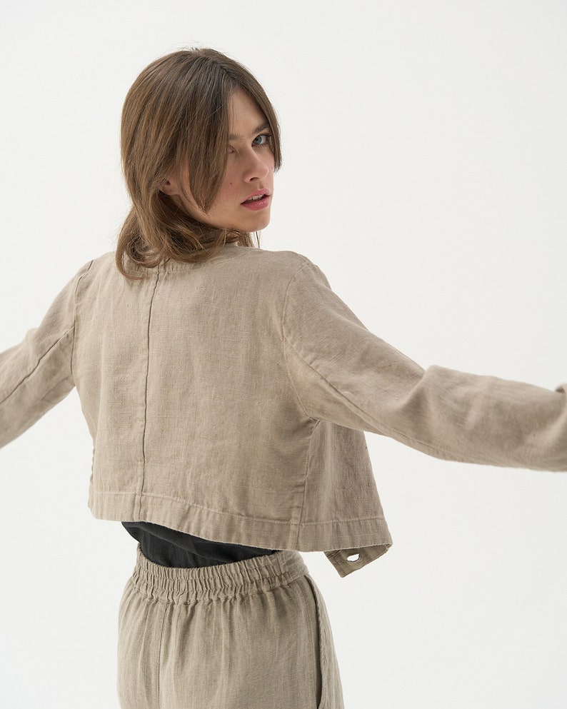 Cropped linen jacket with classic jacket lapels. Back photo. There's a stylised seam placed at the middle back, going through the entire length of the jacket.