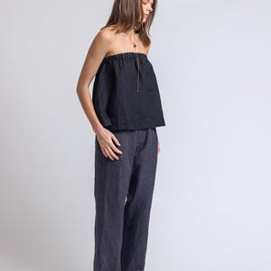 May include: A black strapless top and dark blue pants. The top has a gathered neckline and a drawstring. The pants are wide-legged and made of a similar fabric. The outfit is simple and elegant, suitable for various occasions.