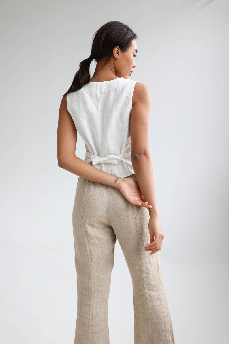 The back photo of linen buttoned vest with a v-neck. Back has an adjustable tie string. Here in white linen.