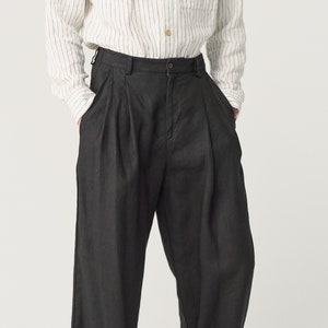 May include: Black pleated pants with a wide leg silhouette. The pants have a high waist and a relaxed fit.
