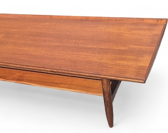 May include: A mid-century modern coffee table made of wood with a lower shelf. The table has a rectangular top with rounded edges and tapered legs.