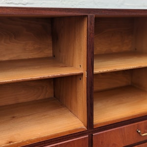May include: A wooden cabinet with multiple shelves and drawers. The cabinet is made of dark wood with a reddish hue. The shelves are empty and ready to be filled with items.