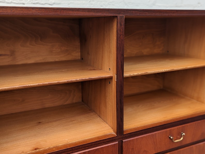 May include: A wooden cabinet with multiple shelves and drawers. The cabinet is made of dark wood with a reddish hue. The shelves are empty and ready to be filled with items.