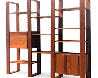 May include: A pair of wooden bookshelves with a warm, reddish-brown finish. Each unit features multiple shelves and a cabinet with doors. The design is minimalist and modern, suitable for displaying books and decor.