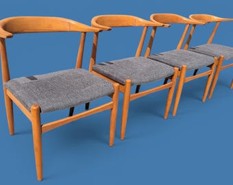 Puede incluir: Un conjunto de cuatro sillas de madera con respaldos curvos y asientos de tela gris. Cada silla presenta una estructura de madera marrón claro con cuatro patas cónicas y un reposabrazos continuo, junto con un cojín de asiento gris texturizado.