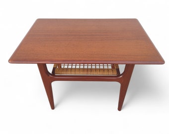 May include: A mid-century modern teak wood coffee table with a woven cane shelf. The table has a rectangular top and four slender legs.