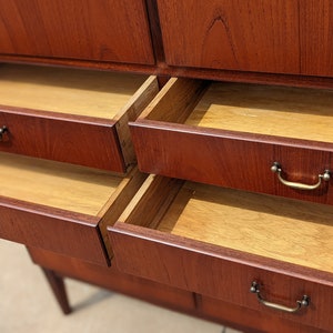 May include: A wooden cabinet with multiple drawers. The drawers are open and reveal a light wood interior. The cabinet is made of a rich reddish-brown wood.