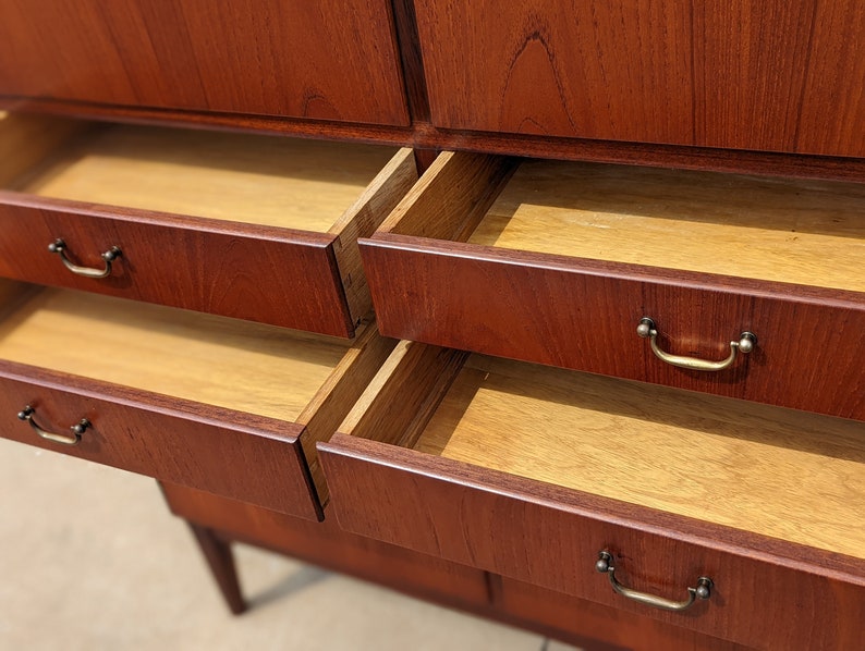 May include: A wooden cabinet with multiple drawers. The drawers are open and reveal a light wood interior. The cabinet is made of a rich reddish-brown wood.