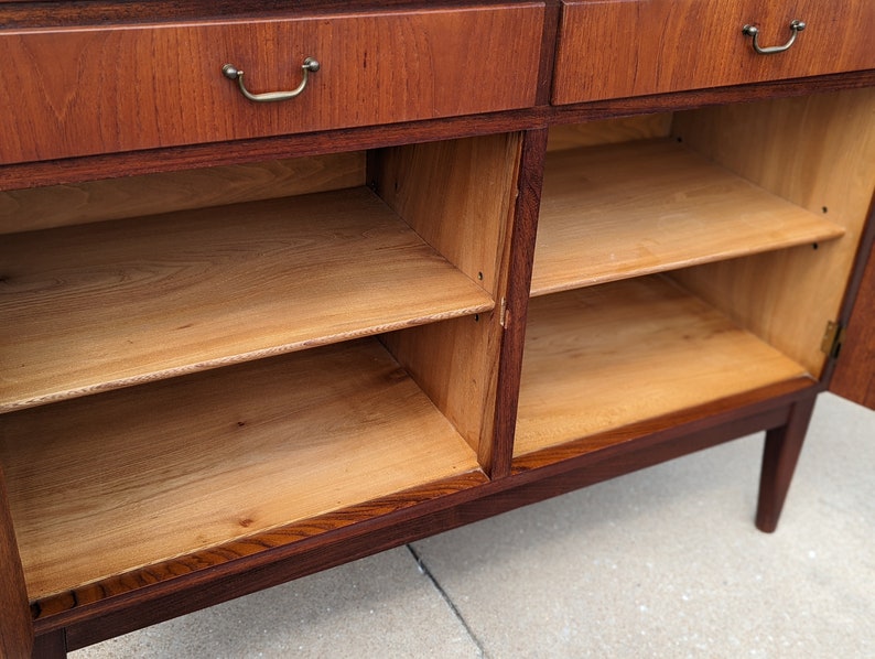 May include: A wooden cabinet with two drawers and two doors. The doors are open, revealing two shelves inside. The cabinet is made of dark wood with a light wood interior.