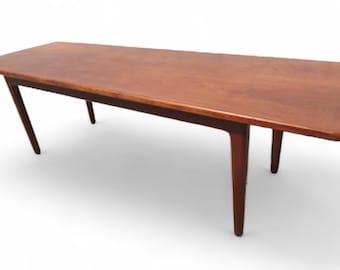 May include: A long, rectangular, wooden coffee table with a dark brown finish. The table has four legs that taper towards the bottom.