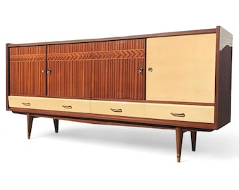 May include: A mid-century modern sideboard with four drawers and three doors. The cabinet is made of wood with a light brown finish and has brass hardware. The doors have a wood grain pattern and the drawers have a light beige finish.