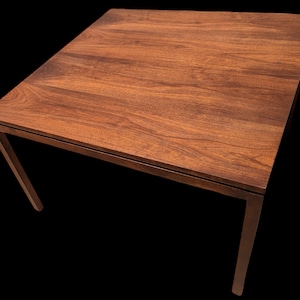 May include: A dark brown wooden table with a rectangular top and four legs. The table is made of solid wood and has a natural finish.