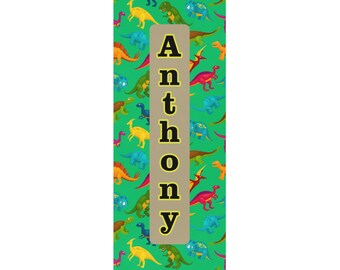 May include: A green bookmark with a pattern of colorful dinosaurs and the name "Anthony" written in black letters on a tan background.