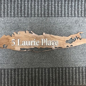 May include: A wooden sign shaped like Long Island, New York, with the text "5 Laurie Place" carved into it.