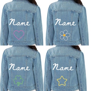 May include: Four light blue denim jackets with white cursive "Name" text on the back. Each jacket features a different embroidered design: a pink heart, a white flower with a yellow center, a green shamrock, and a yellow star.