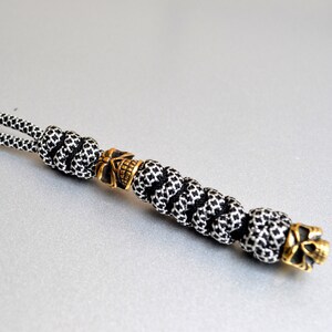 May include: Black and white paracord keychain with two gold skull beads.