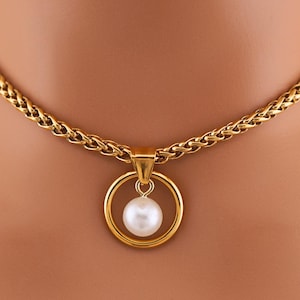 May include: A gold chain necklace with a circular pendant featuring a single white pearl.