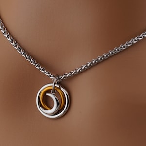 May include: A silver chain necklace with a pendant featuring two interlocking circles, one silver and one gold.