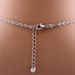 May include: Close-up of a silver-colored necklace clasp and adjustable chain. The chain is made of small, interconnected links. The clasp is a lobster claw style. The necklace is displayed on a mannequin.
