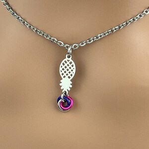 Puede incluir: Un collar de cadena de plata con un colgante de pi&ntilde;a y un amuleto azul, rosa y blanco.