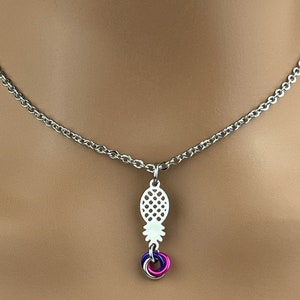 Puede incluir: Un collar de cadena plateada con un colgante de pi&ntilde;a y un conjunto de tres anillos entrelazados en morado, rosa y plateado.