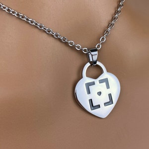 May include: A silver heart-shaped pendant necklace with a black square design and a small heart in the center.