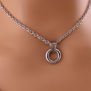 Peut inclure: Un collier en cha&icirc;ne argent&eacute;e avec un pendentif rond simple. Le pendentif est compos&eacute; de deux cercles, l'un l&eacute;g&egrave;rement plus grand que l'autre.