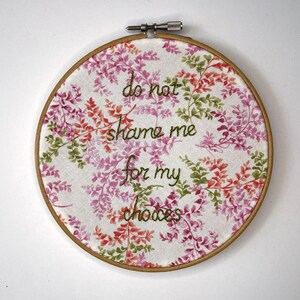 May include: Embroidered hoop art with a floral pattern and the text "do not shame me for my choices".