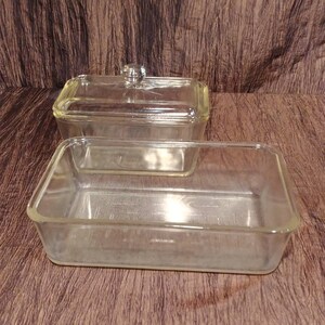 May include: Two clear glass baking dishes, one with a lid. The dishes are rectangular and have a smooth, shiny surface.