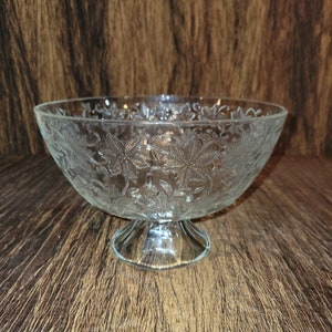 May include: A clear glass bowl with a pedestal base. The bowl has a floral design etched into the glass.