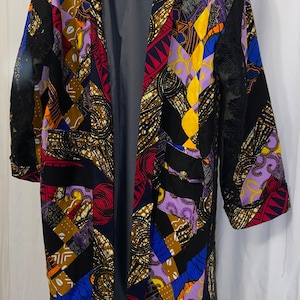 May include: A long, open-front coat with a patchwork design. The coat features a variety of colorful patterns, including geometric shapes and floral motifs. The coat has a gray lining and black lace accents. The coat is approximately 45 inches long.