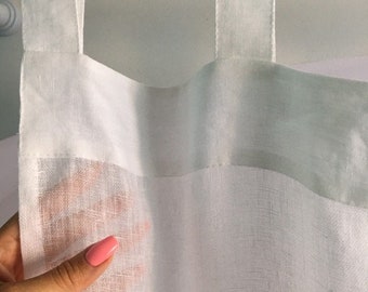 May include: White sheer curtain panels with a linen texture, hanging from a white curtain rod. The curtain panels have a simple, modern design and are perfect for adding a touch of elegance to any room.