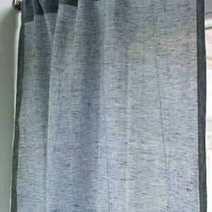May include: A sheer linen curtain with a dark gray border. The curtain is hanging from a silver curtain rod.