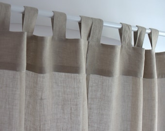 May include: Beige linen curtains with a textured weave, hanging from a white curtain pole. The curtains have a simple design with a single fold at the top and a double fold at the bottom.