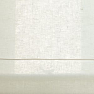 May include: A close-up of a cream-colored Roman shade made of a textured fabric. The shade is partially lowered, revealing a glimpse of the window and a decorative spool at the bottom. The fabric appears to be linen or a similar material.