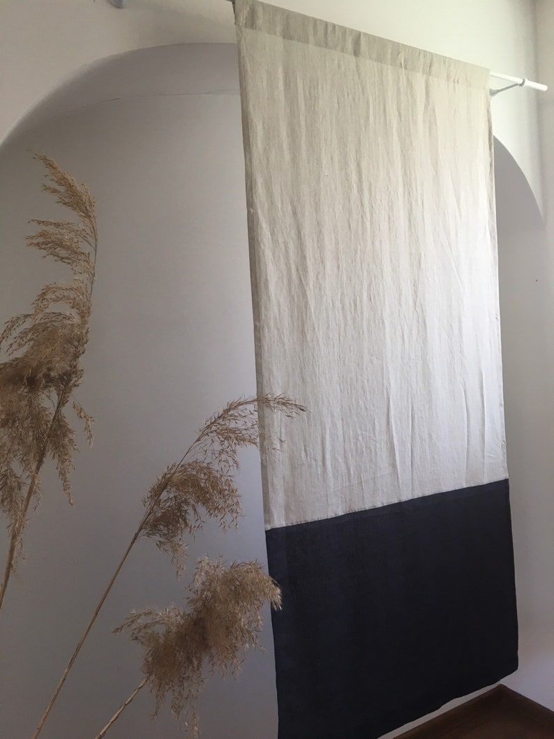 Puede incluir: Cortina rectangular de lino de dos tonos. La parte superior es de color beige claro y la inferior es negra. La cortina cuelga de una barra blanca, creando una est&eacute;tica minimalista. La tela parece ligeramente texturizada. Altura aproximada: 200 cm.