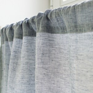 May include: A set of white linen curtains with a darker gray top border. The curtains are hung on a silver curtain rod.