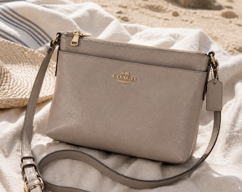 Borsa a tracolla Coach Journal in pelle martellata color tortora, beige e oro.
