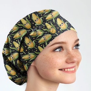 May include: A black scrub cap featuring a repeating pattern of smiling corn on the cob with green leaves and small yellow stars. The cap is made of a soft, flexible material.
