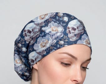 Peut inclure: Une charlotte de bloc opératoire avec un fond bleu foncé orné d'un motif répétitif de crânes humains blancs et gris entremêlés de fleurs bleu clair et blanches. Ce couvre-chef en tissu présente une forme arrondie et ajustée.
