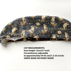 May include: A navy blue cap with a repeating pattern of otters, flowers, and foliage in shades of brown and cream. The cap's front height is 4.7 inches, and the circumference is adjustable from 21.2 to 25.6 inches. It has a sweatband on the front inside.