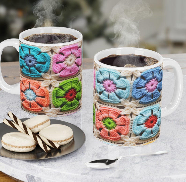 Puede incluir: Dos tazas de cer&aacute;mica blanca con un patr&oacute;n de flores de ganchillo de colores. Las tazas est&aacute;n llenas de caf&eacute; y sale vapor de ambas tazas.